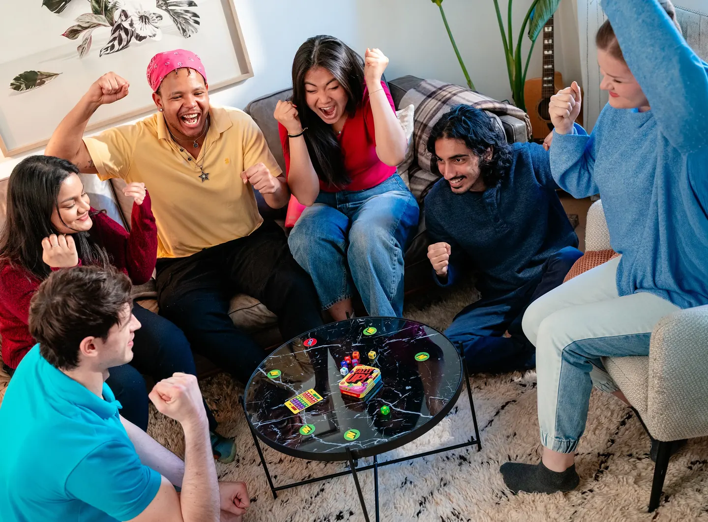 Six friends cheering around a coffee table mid-game of Tally Up